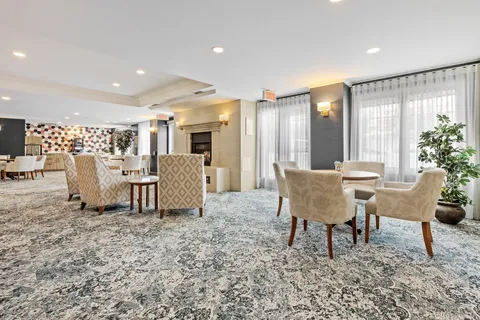 Room with upholstered chairs, tables, patterned carpet and broad windows