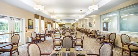 Dining room with rows of set tables and round-backed chairs