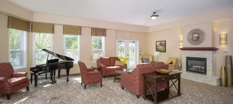 Room with patterned armchairs, a piano and a fireplace