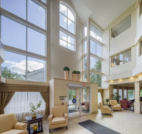 Entrance hall with tall windows, glass doors and upholstered chairs