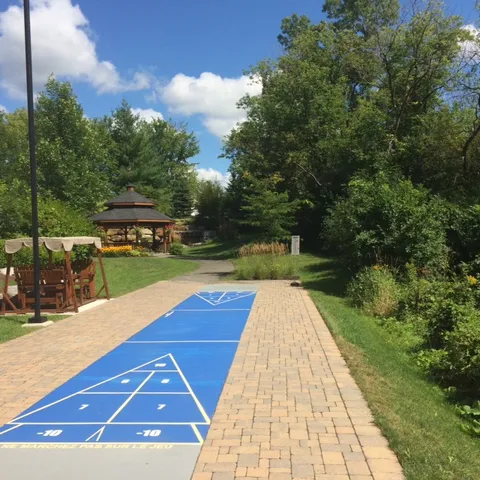 Outdoor shuffleboard court beside trees and a gazebo.