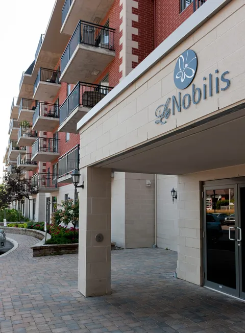 Covered entrance with glass doors and balconies above.