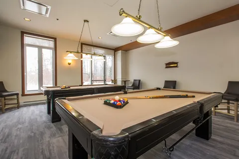 Billiards room with two pool tables and overhead lights.