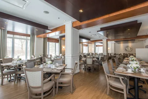 Dining room with set tables, chairs and tall windows.