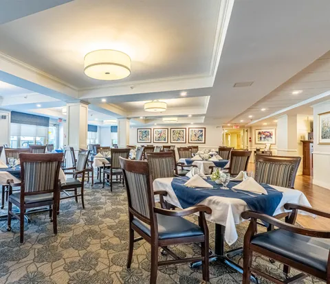 Dining room with set tables, upholstered chairs and ceiling lights.