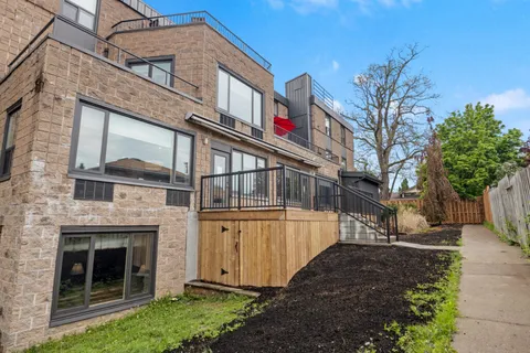 Side of the residence with a terrace, railing and planted garden bed.