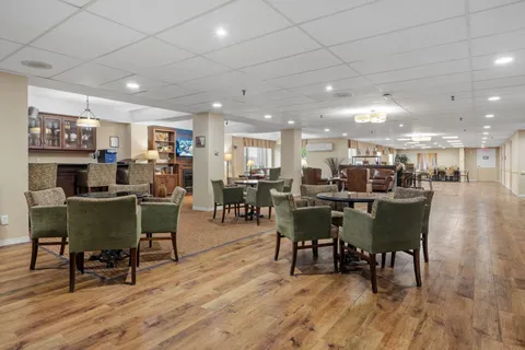 Open lounge with armchairs, tables and a fireplace.