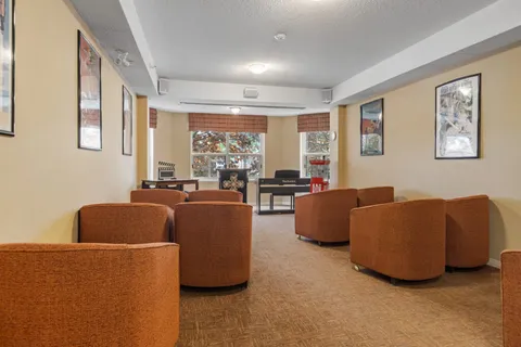 Corridor seating area with upholstered chairs and framed pictures.