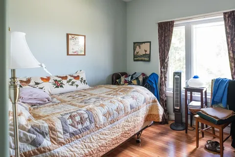 Bedroom with a patchwork quilt, bird-patterned pillows and a large window