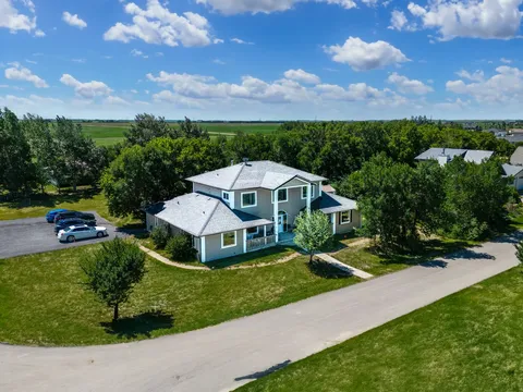Aerial view of the residence, lawn, trees and parked cars beside the road