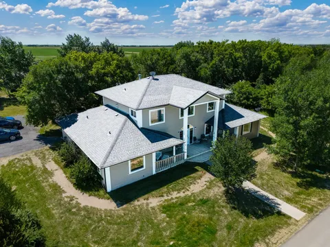 Aerial view of the residence with a covered porch, trees and a path to the road