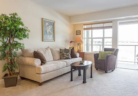 Room with a sofa, armchair, coffee table and large windows