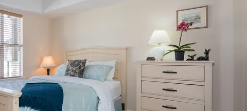 Bedroom with a bed, bedside lamp, dresser and orchid