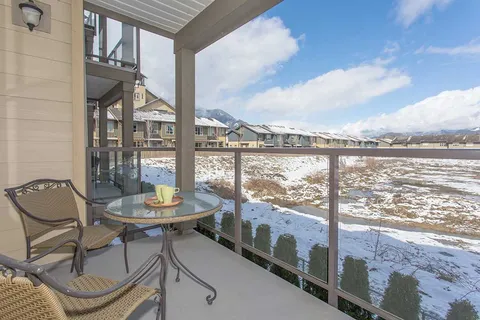 Covered balcony with wicker chairs and a glass table overlooking snowy grounds