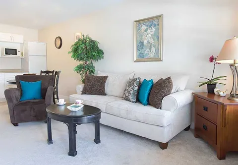 Sitting area with a sofa, armchair, round table and kitchenette