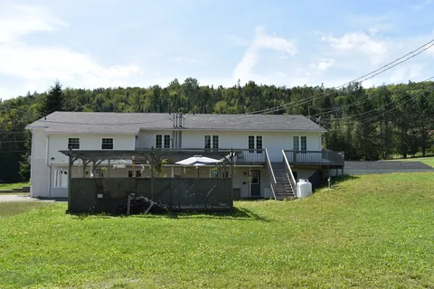 Rear of the residence beside a lawn and fenced deck.