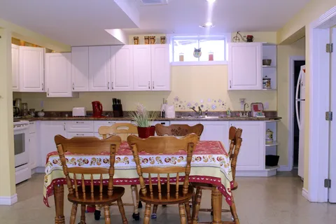 Dining table beside a shared kitchen with white cabinets.