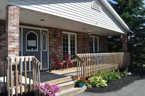 Covered porch entrance with access ramp and flower pots.