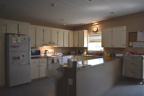 Shared kitchen with refrigerator, cabinets and work counter.