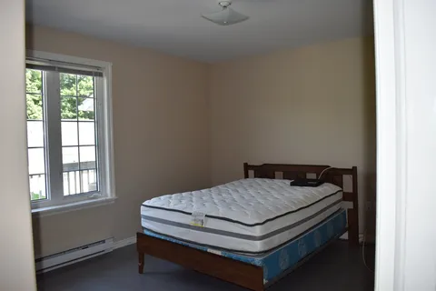 Bedroom with a wooden bed frame and window.