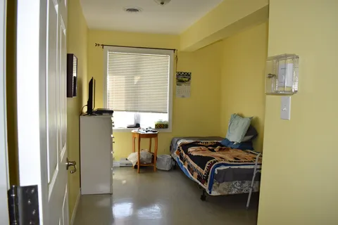Bedroom doorway with a bed, chair and window.