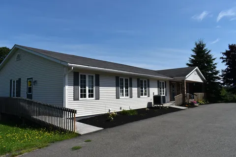 Single-storey residence with white siding and front ramp.