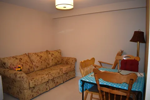 Sitting area with a sofa, table and wooden chairs.