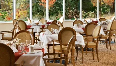 Dining room with tables and upholstered chairs beside large windows