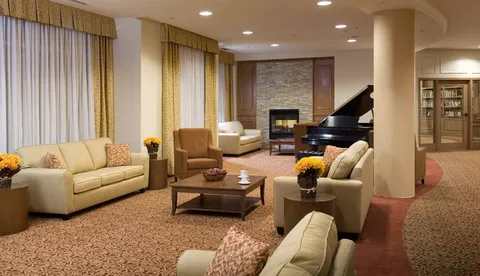 Room with sofas, a fireplace, a grand piano and large windows