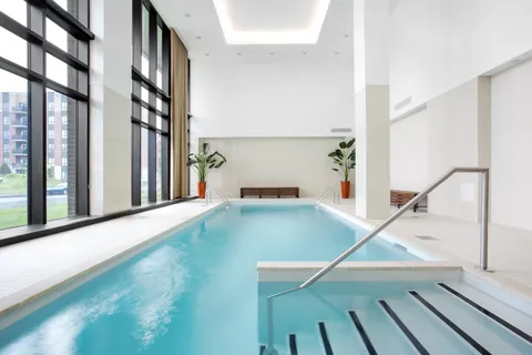 Indoor swimming pool with tall windows and a handrail.