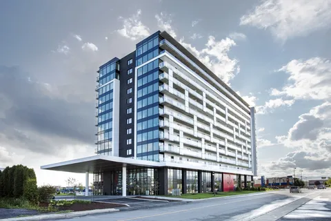 Tall residence building with glass balconies and a covered entrance.