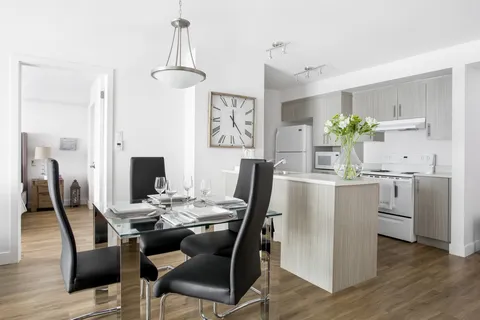 Apartment kitchen and dining table with black chairs.