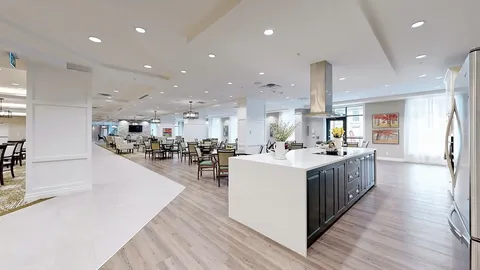 Kitchen island with dark cabinets in an open room with dining tables