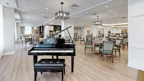 Grand piano beside tables and chairs in an open room