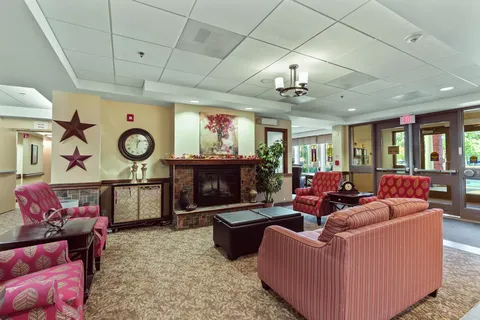 Pink armchairs and a striped sofa around a fireplace