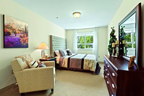 Bedroom with a double bed, dresser and upholstered chair