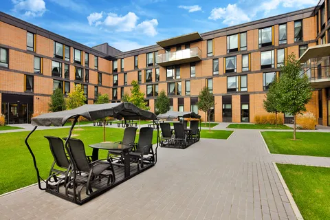 Residence buildings around a green courtyard with paths and covered outdoor seating