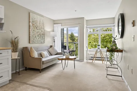 Suite living room with a sofa, kitchenette and balcony doors.