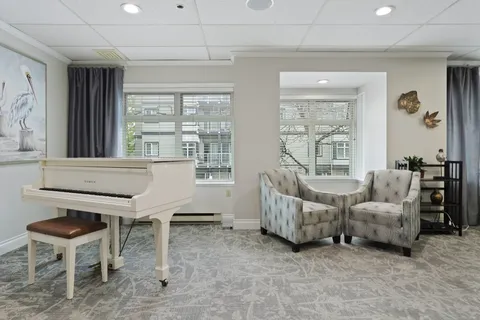 Lounge with a white piano and armchairs by the window.