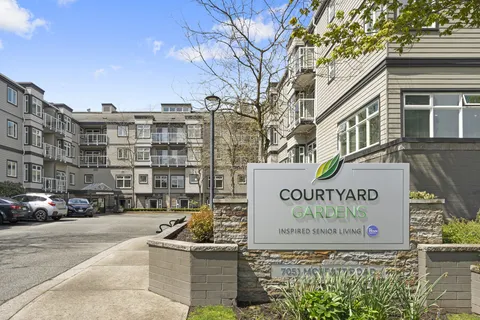 Residence exterior and driveway beside the Courtyard Gardens sign.