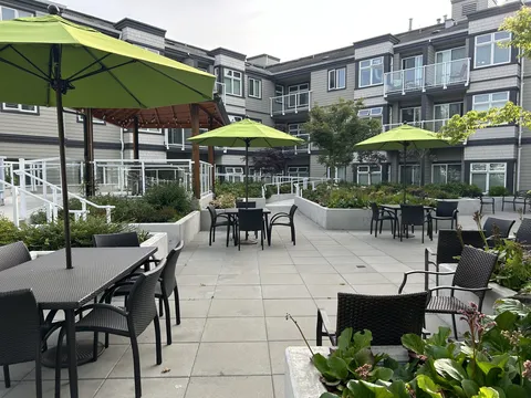 Courtyard patio with tables, chairs, green umbrellas and planted beds.