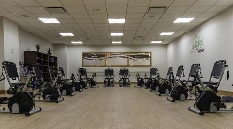 Exercise room with stationary bicycles, a wood floor and a mirrored wall.
