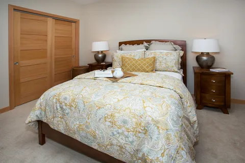 Bedroom with a wood headboard, bedside lamps, a tray and closet doors.
