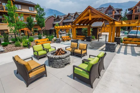 Patio with a fire pit, colourful chairs and a covered pavilion.