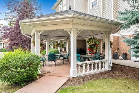 Covered patio with outdoor chairs, tables and hanging flower baskets