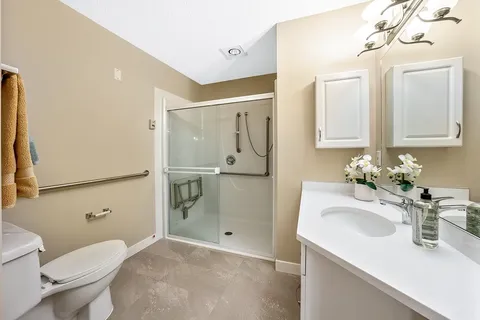 Bathroom with a sink, toilet, walk-in shower and grab rails