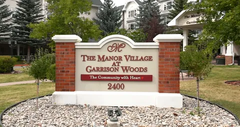 Residence sign beside a lawn, trees and the entrance