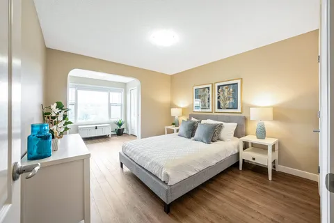 Bedroom with a grey bed, matching lamps and framed botanical artwork