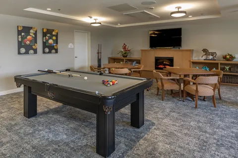 Games lounge with billiards table and seating around a fireplace.