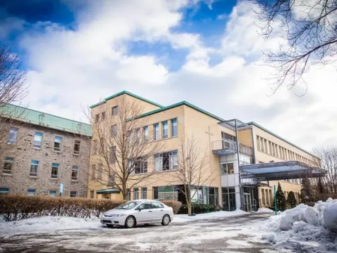 Residence exterior with a covered entrance, a parked car and snowbanks